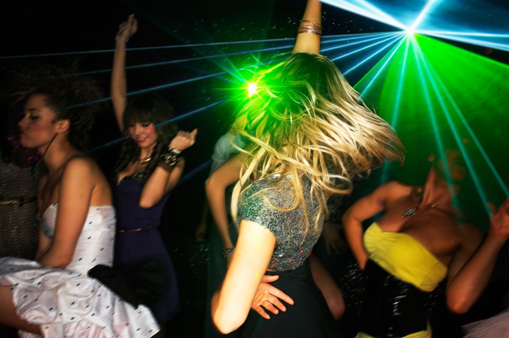 Groupe de jeunes dansant dans une boîte de nuit avec un éclairage laser.