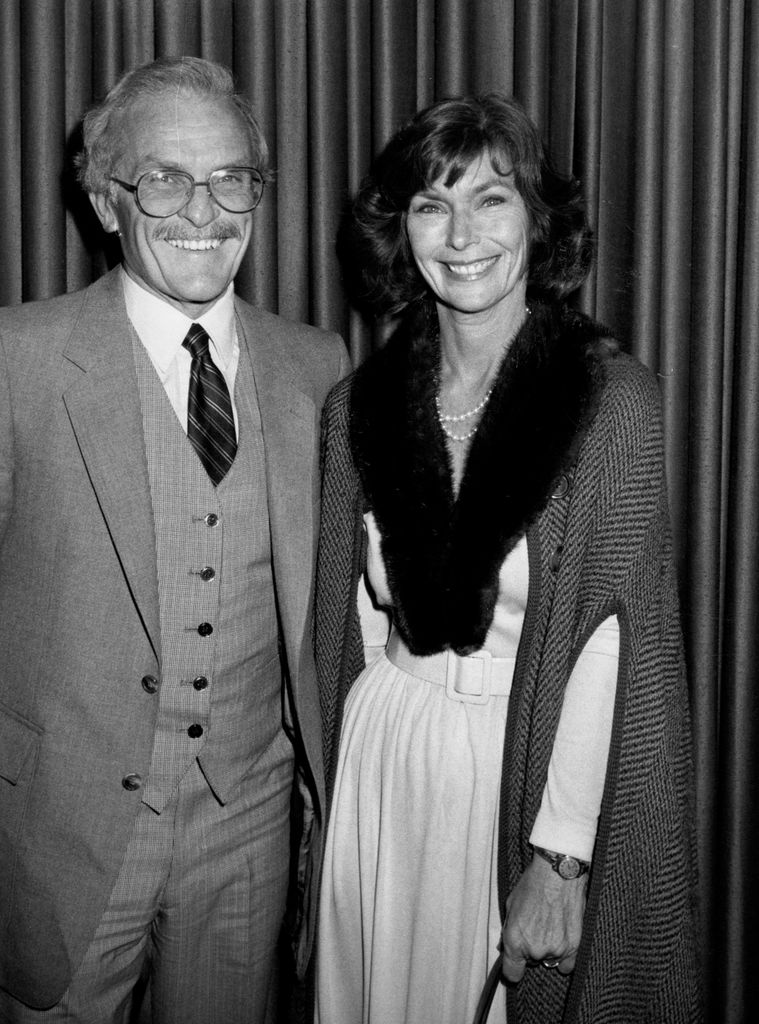 Priscilla Pointer in a white dress and fur shawl and Robert Symonds in a suit