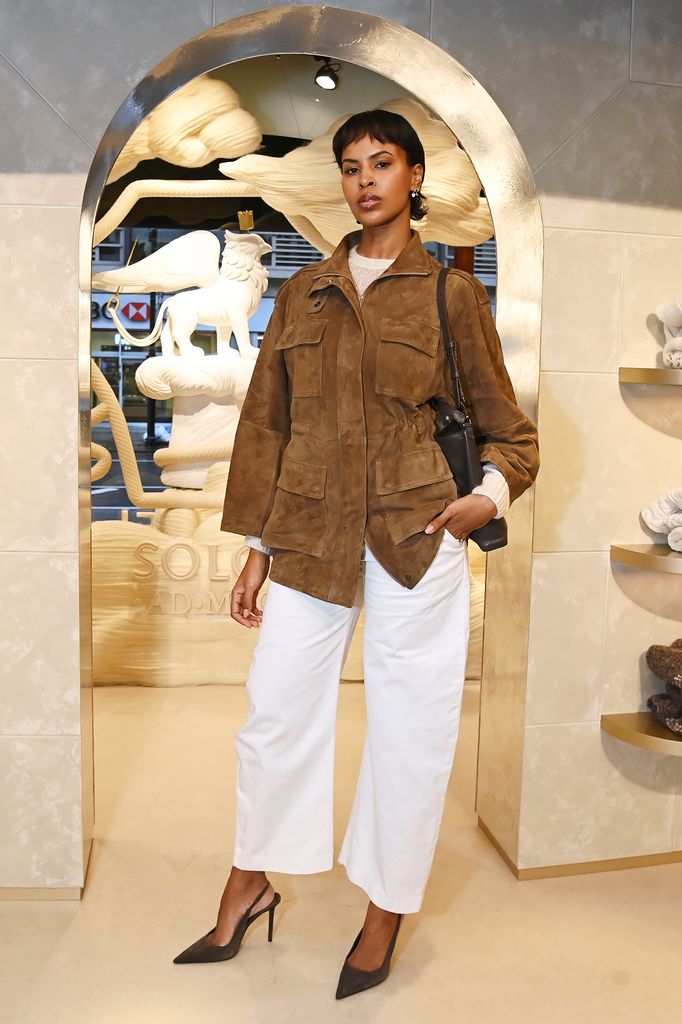 Sabrina Elba posed in fashion shop in white trousers and tan suede jacket