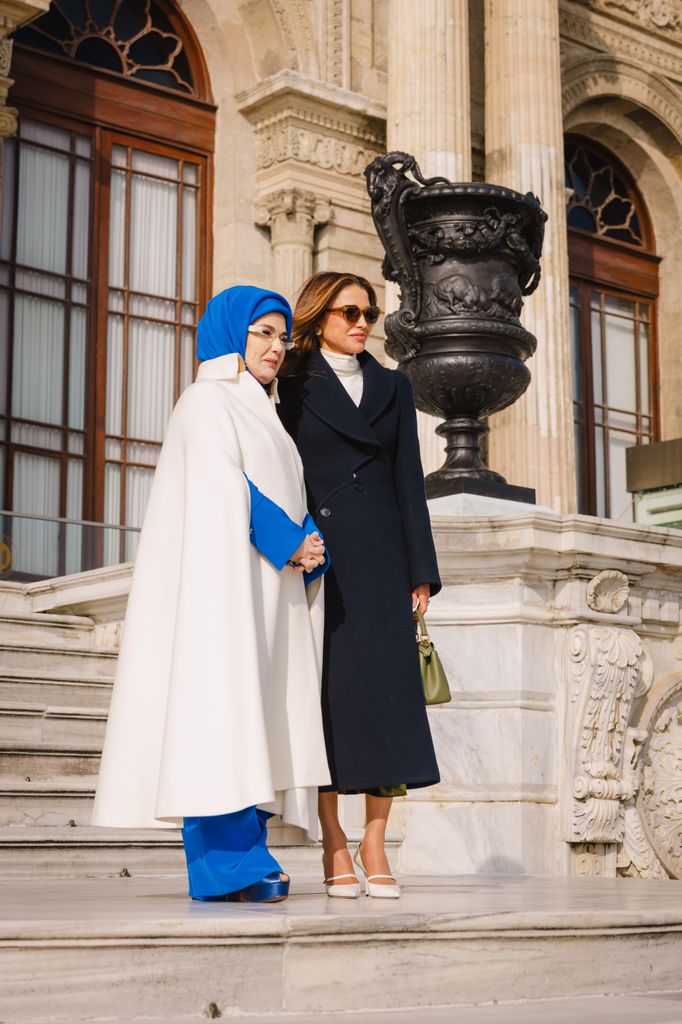 La reine Rania en manteau sur les marches du palais avec la première dame turque