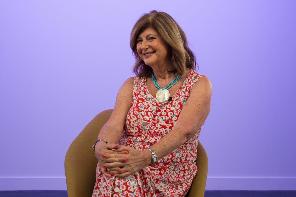 Woman smiling in a floral print dress on a purple background 