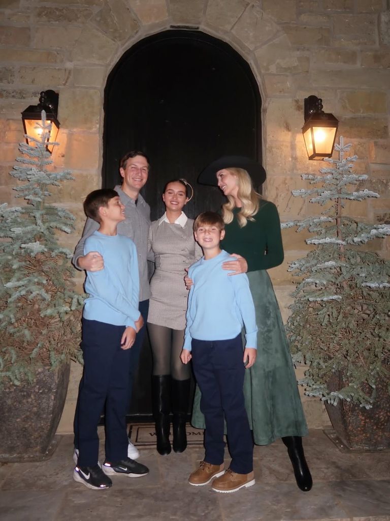 Ivanka Trump is green skirt posing with family next to Christmas trees