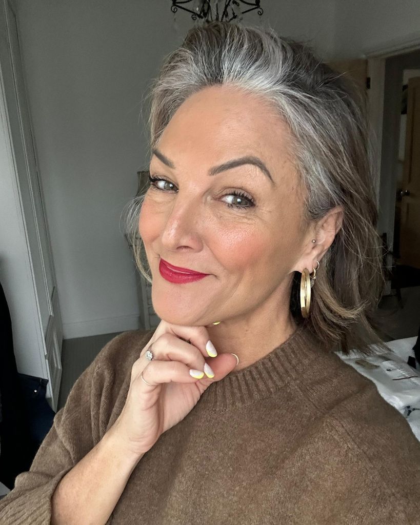 Woman posing for a selfie with red lipstick and grey hair 