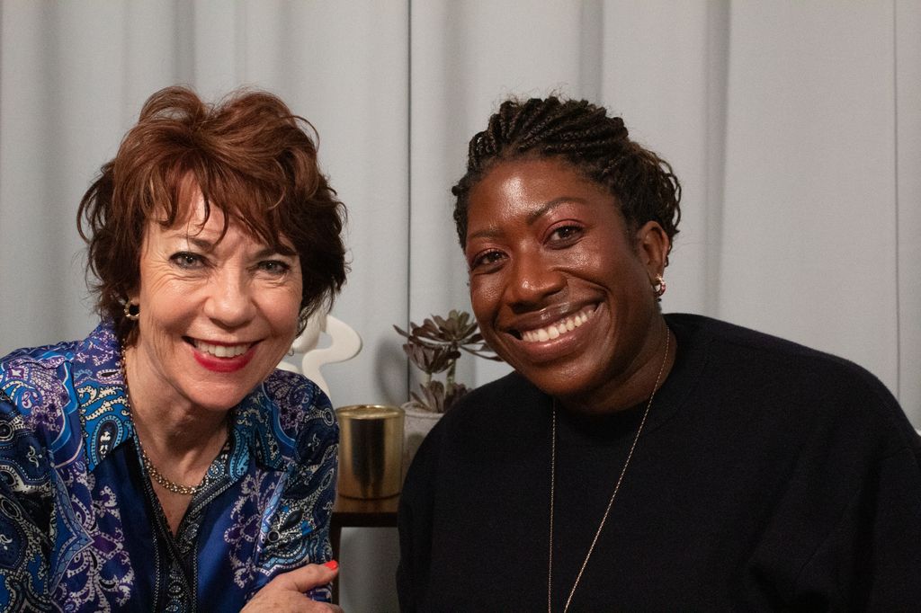Two women smiling in a podcast studio 