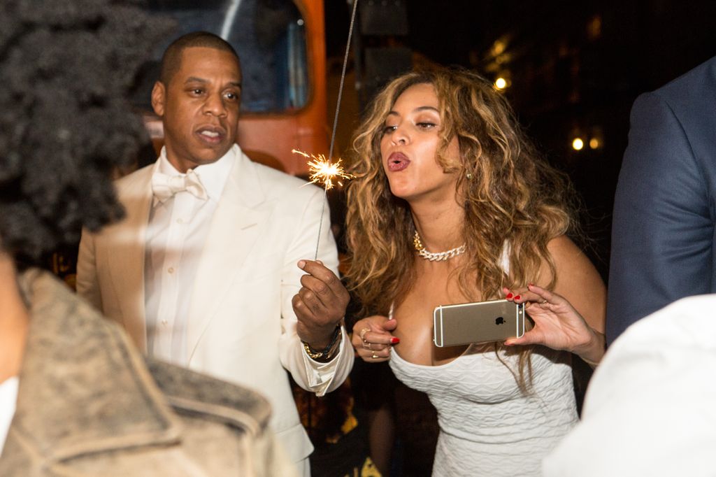 Beyonce in white blowing on sparkler held by jay z