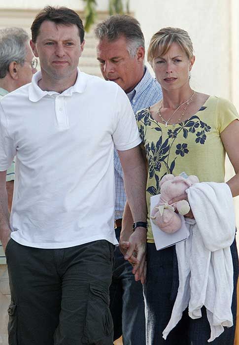 Gerry and Kate McCann holding hands. Kate is holding a pink stuffed toy of Madeleines