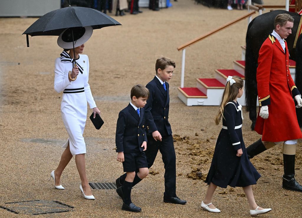 La princesse Kate s'abrite de la pluie avec un parapluie alors qu'elle retourne avec ses enfants au Glass State Coach lors de la Horse Guards Parade pendant Trooping the Color.