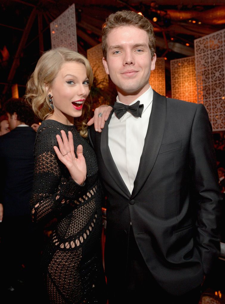Taylor Swift posing and waving with her brother Austin Swift at a fancy event
