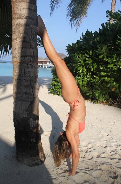 Elizabeth Hurley doing a handstand up against a palm tree
