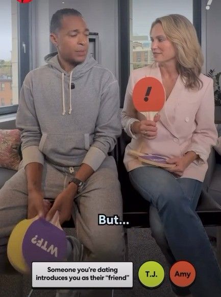 amy robach and tj holmes holding up paddles
