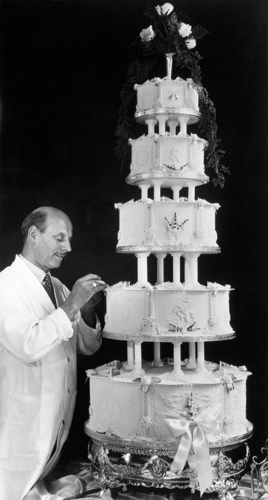 baker putting the finishing touches to five tier cake