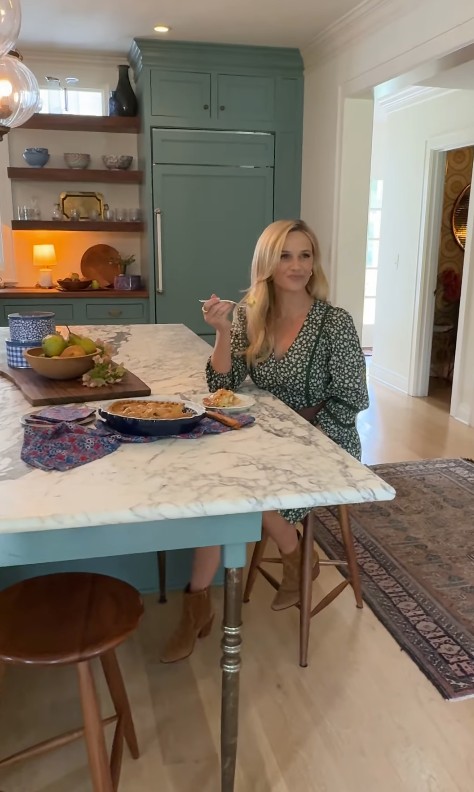 Reese Witherspoon sitting at kitchen table in a stunning green dress 