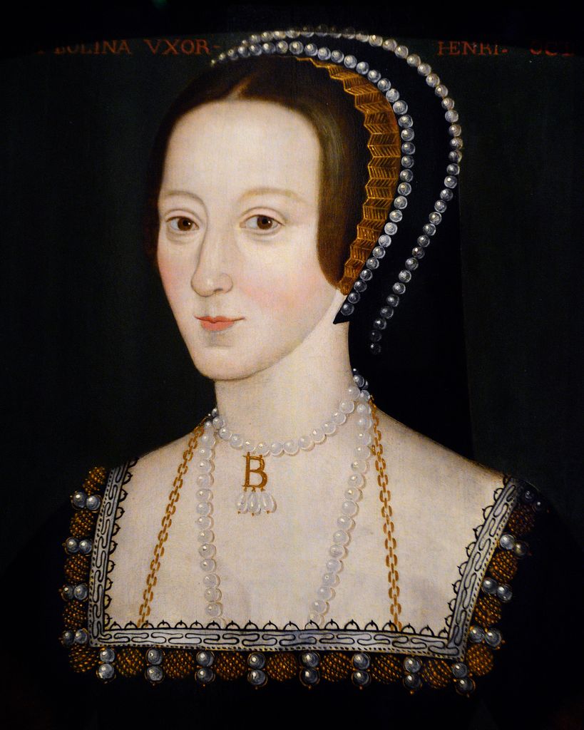 Anne Boleyn wearing a black and brown headdress with a B pearl necklace