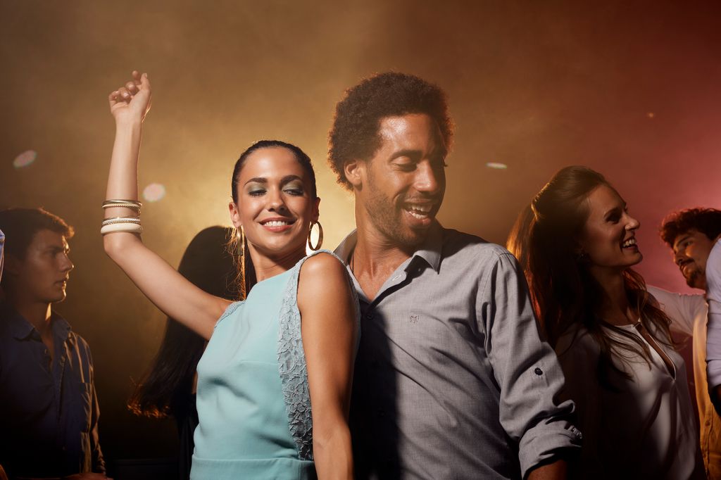 Happy multi-ethnic young couple enjoying on dance floor in nightclub