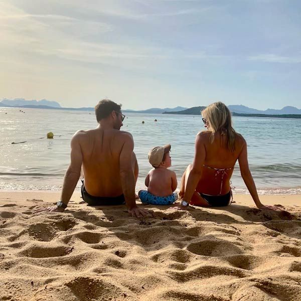 Jamie and Frida Redknapp sitting on the beach with their son Raphael