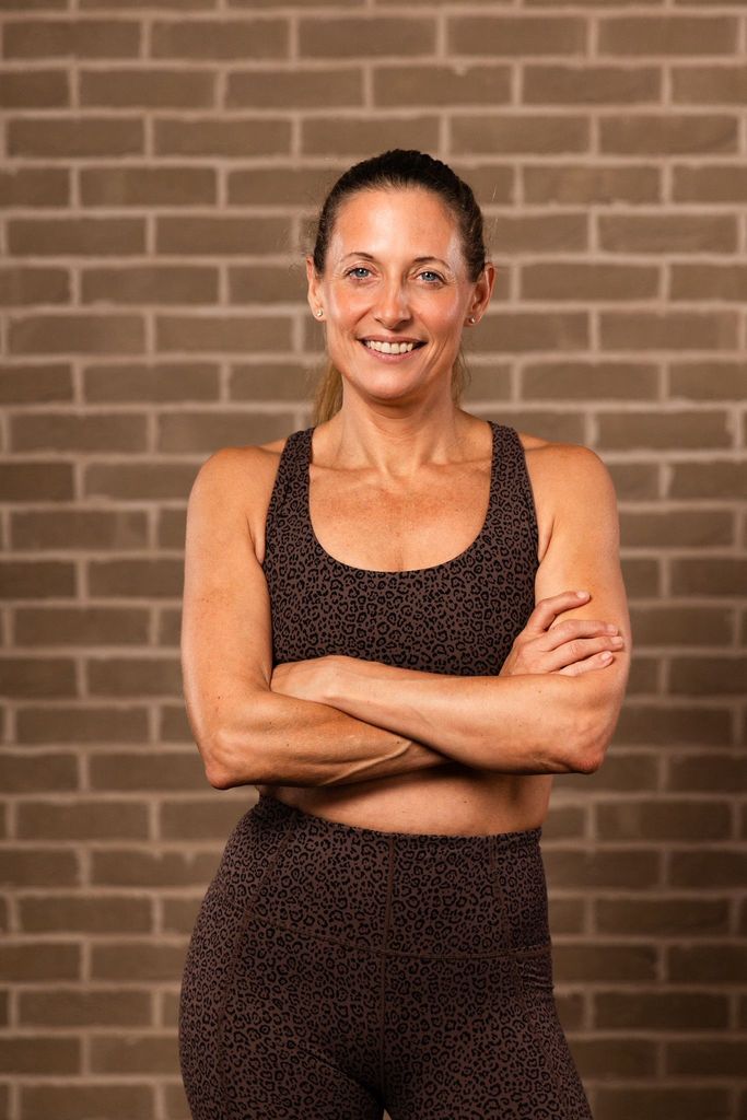 fitness trainer with her arms crossed wearing activewear smiling 