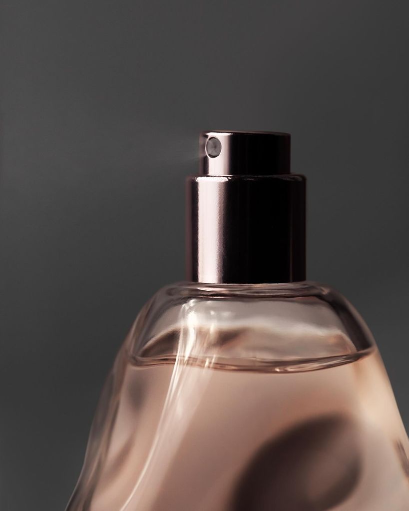 close up of a perfume bottle spraying 