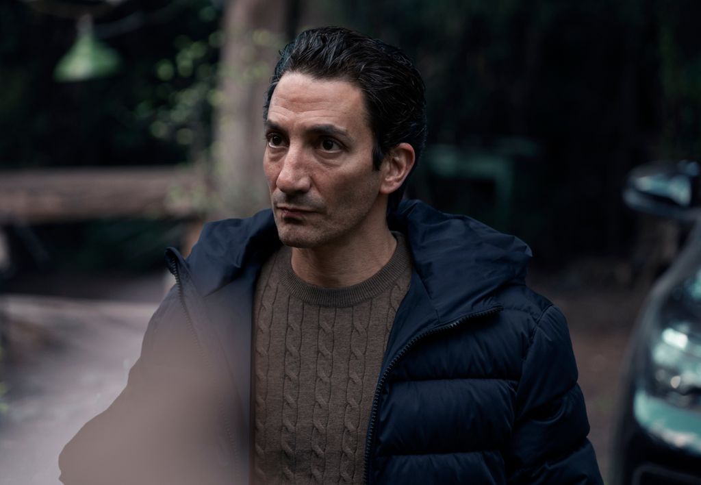 A man in knitwear and a warm coat looks serious