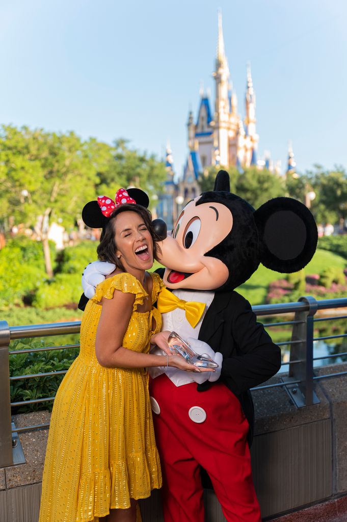 Janette Manrara looking happy as she gets a kiss from Mickey Mouse