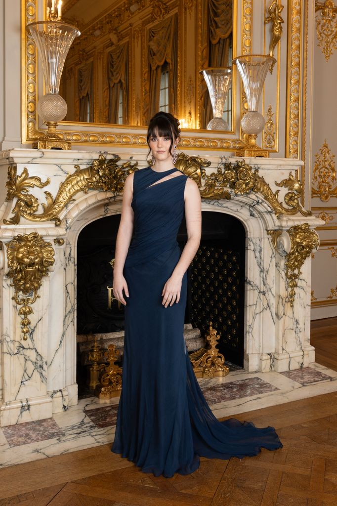 Eirini Zarifi in navy dress against grand fireplace