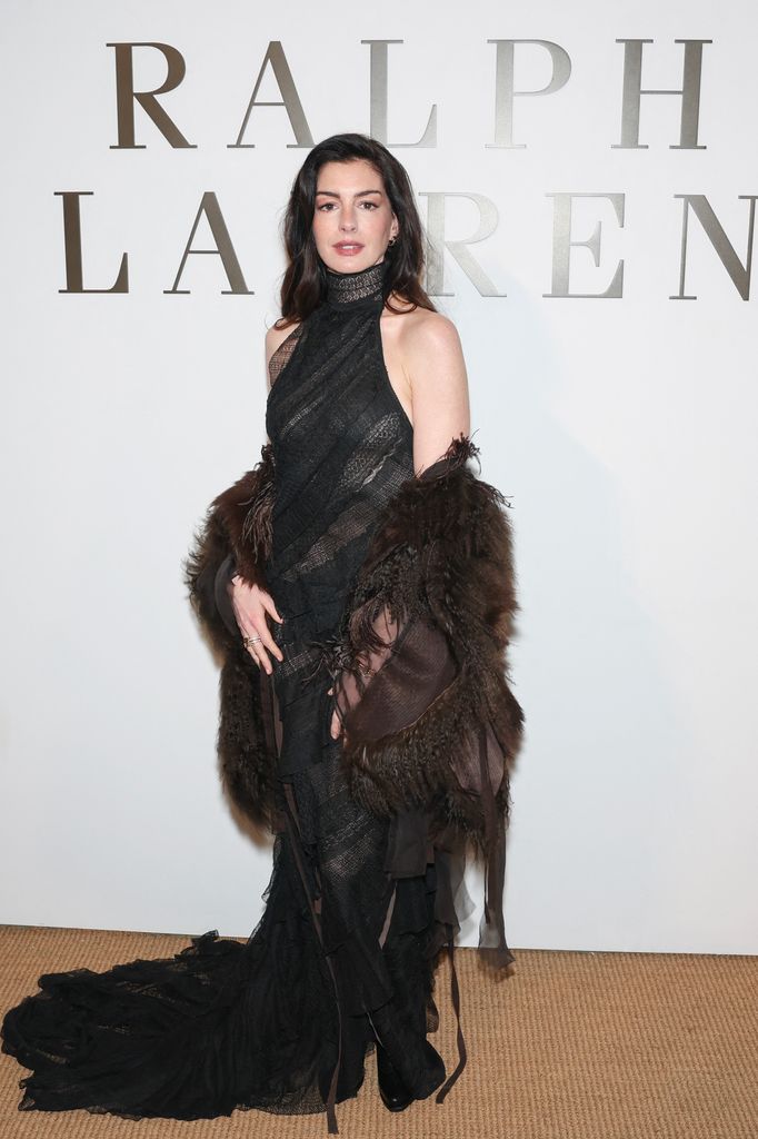 Anne Hathaway porte une robe transparente avec une veste duveteuse drapée sur ses épaules