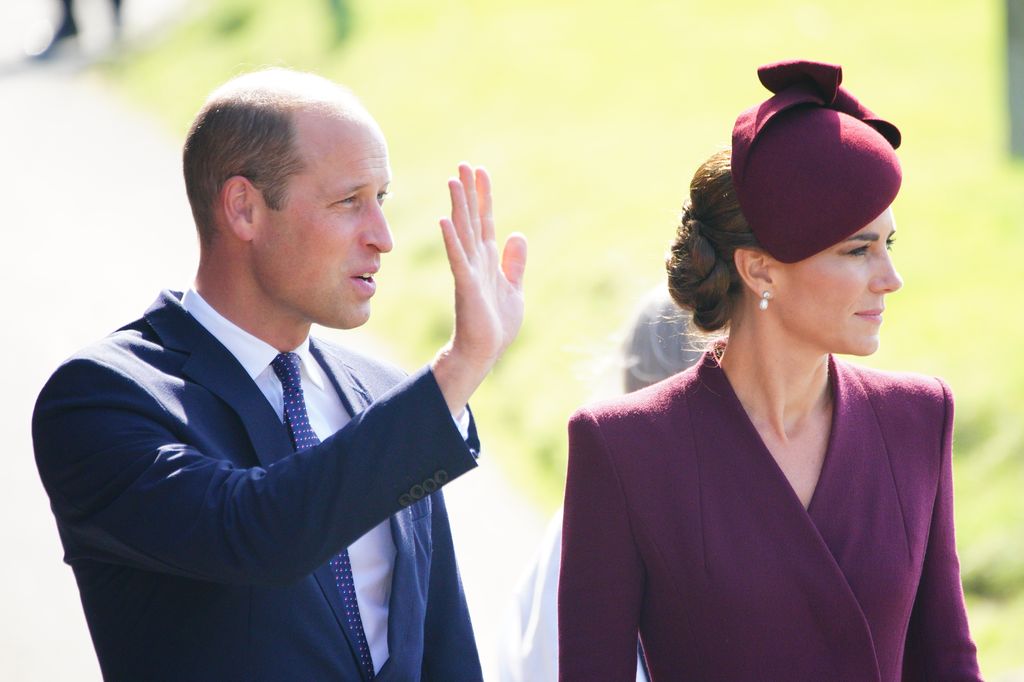 Prince William waving to crowds and Princess Kate in maroon coatdress at St Davids Cathedral 