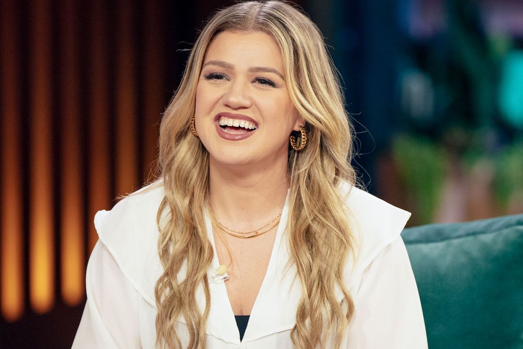 Kelly Clarkson smiling in a monochrome outfit and gold jewellery