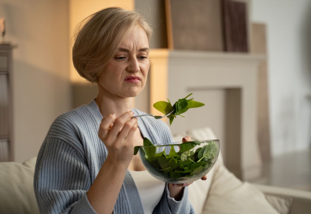   femme faisant face à l'aversion pendant qu'elle mange une salade fade et ennuyeuse
