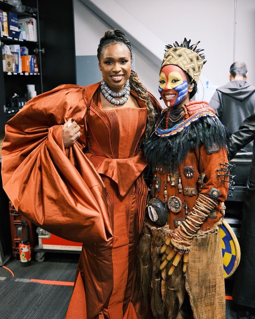 Jennifer Hudson in a bronze gown with a performer from The Lion King 