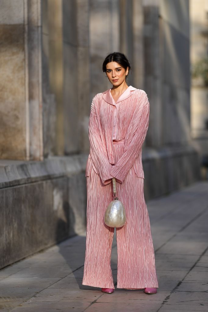 Katie Giorgadze wears Dior earrings, pleated pink pyjama trousers