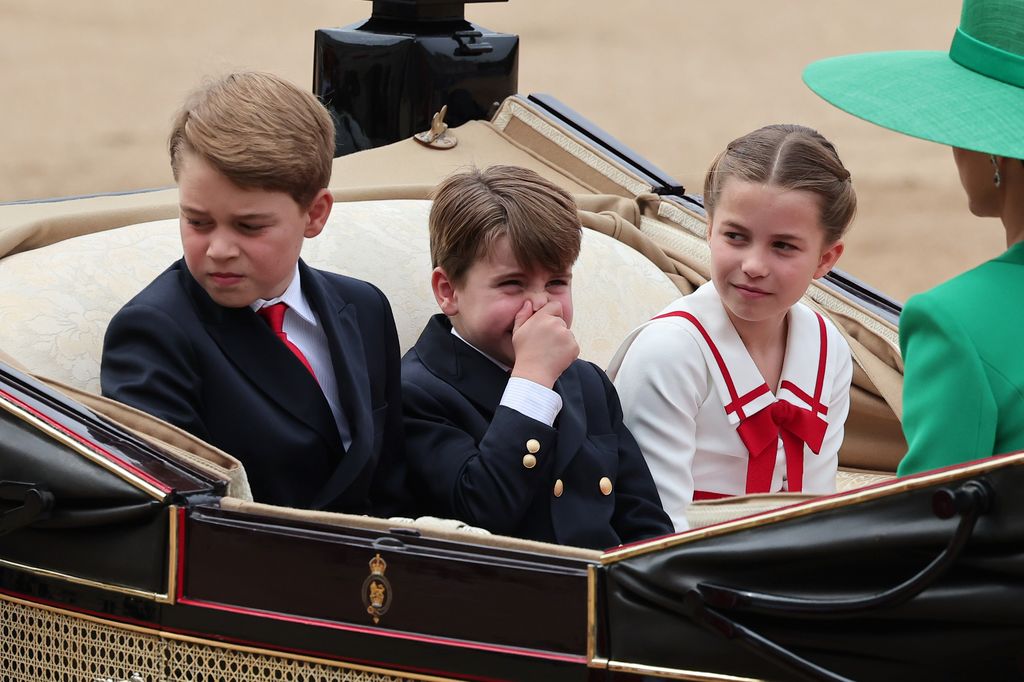 Prince George holding his nose in the carriage next to Princess Charlotte and Prince Louis