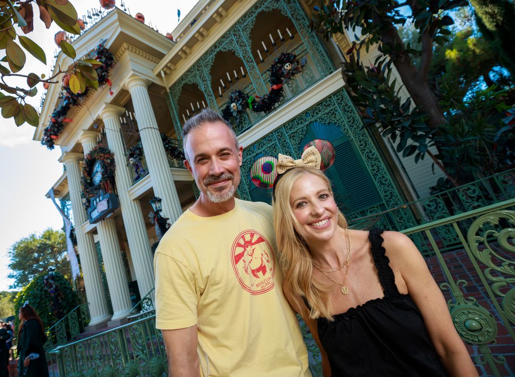 Freddie Prinze Jr. and Sarah Michelle Gellar pose in front of Haunted Mansion Holiday at Disneyland Park, while visiting the park with their family 