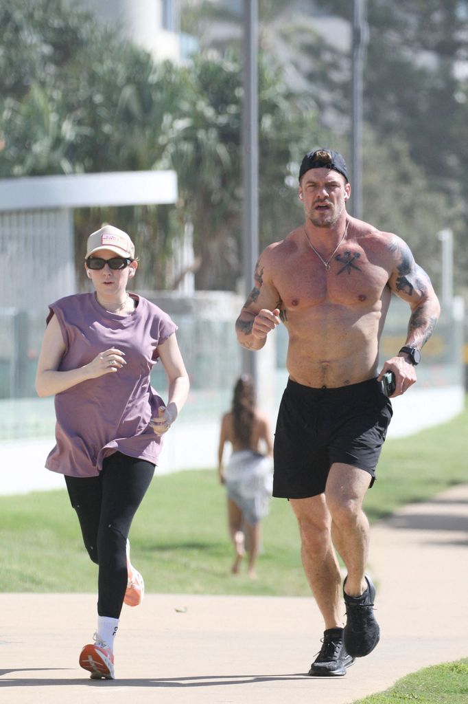 Alan running showing off tattoos with wife alongside him 