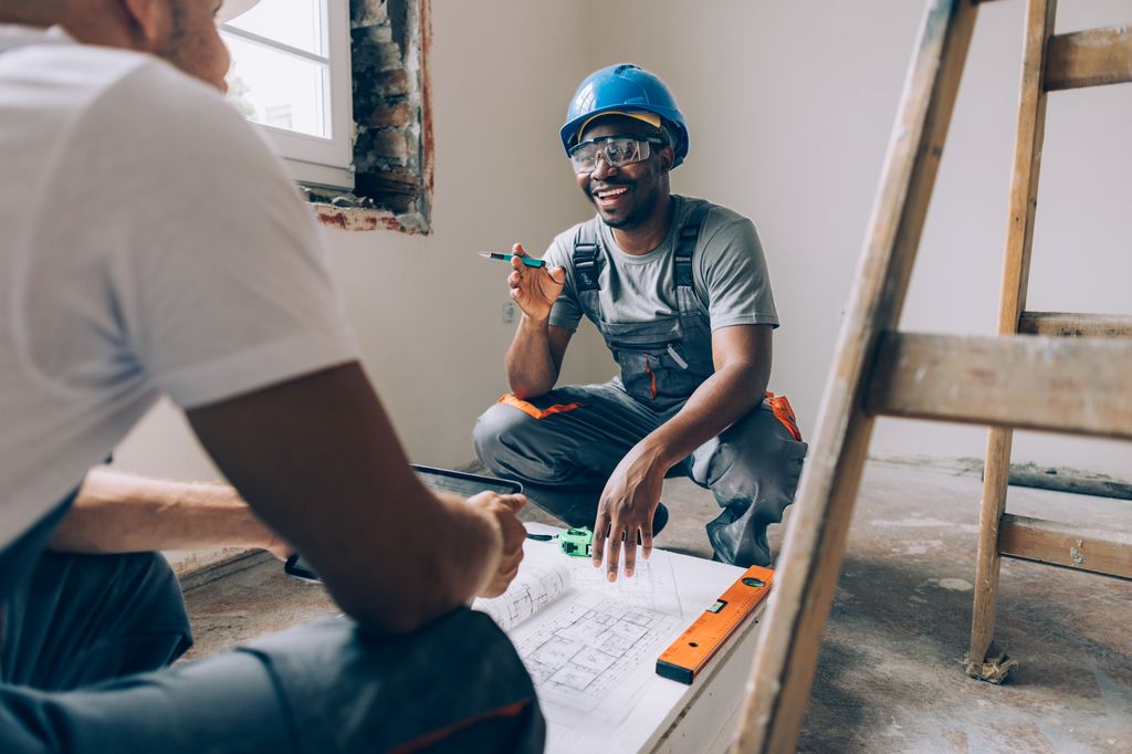 two men discussing building work inside undecorated room
