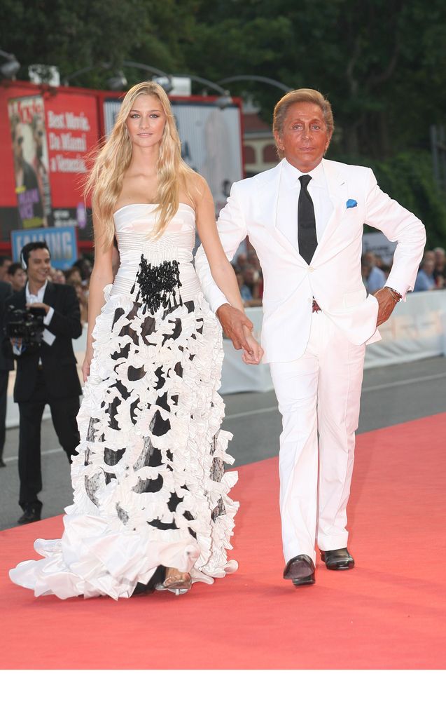Beatrice Borromeo wearing a dramatic black-and-white Valentino ruffle gown alongside Valentino Garavani at a red carpet event, exuding glamour with flowing hair and monochrome embellishment.