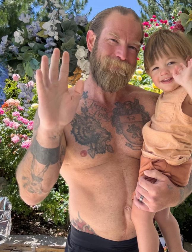 Sean Brosnan shirtless and carrying his son Marley