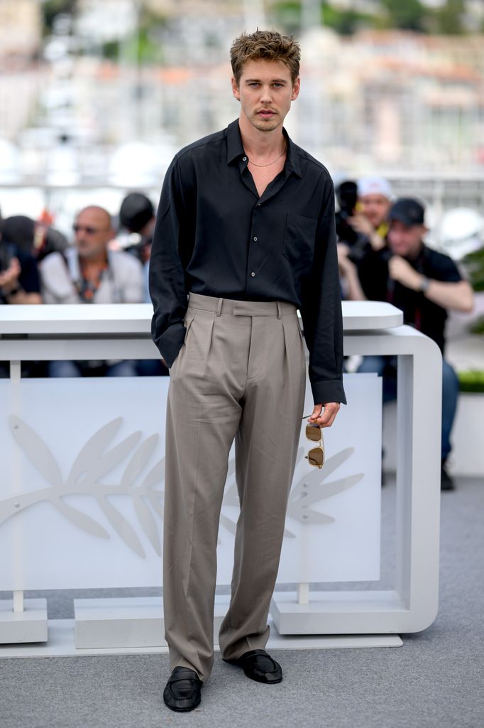 Austin Butler in a black shirt and grey trousers