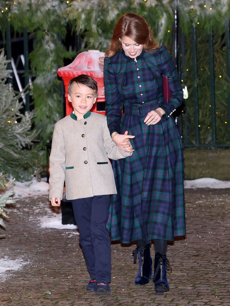 Princess Beatrice holding hands with her stepson, she is wearing a long green and blue tartan coat and velvet blue boots