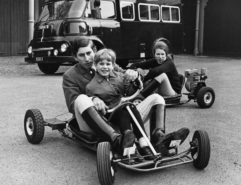 Prince Charles driving a go-kart with Prince Edward on his lap; Princess Anne is in a separate go-kart
