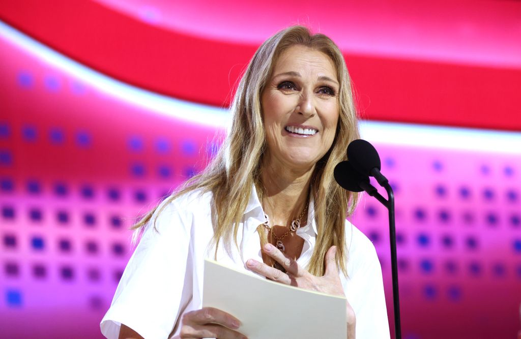 Celine Dion in a white dress reading from a sheet of paper