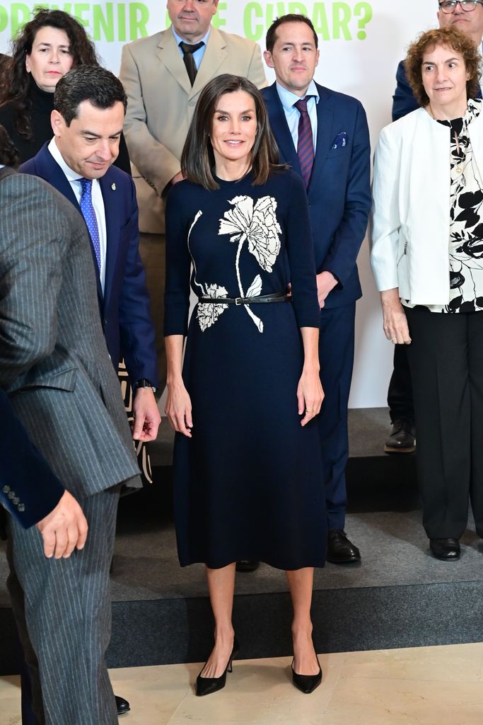 Queen Letizia in dress with floral design surrounded by people