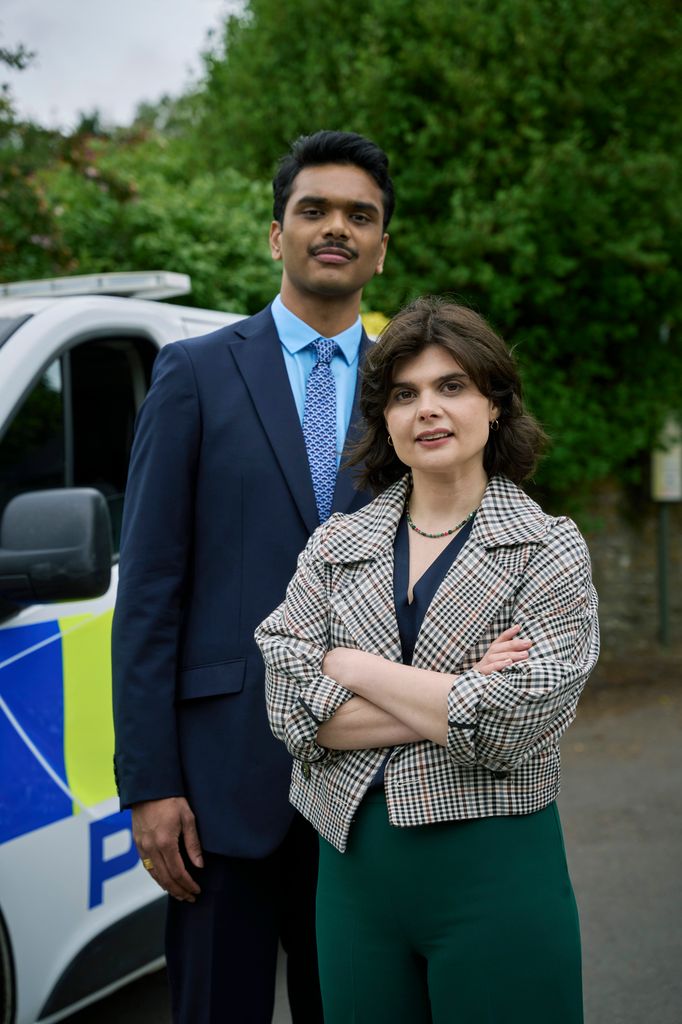 two police detectives standing in front of police van