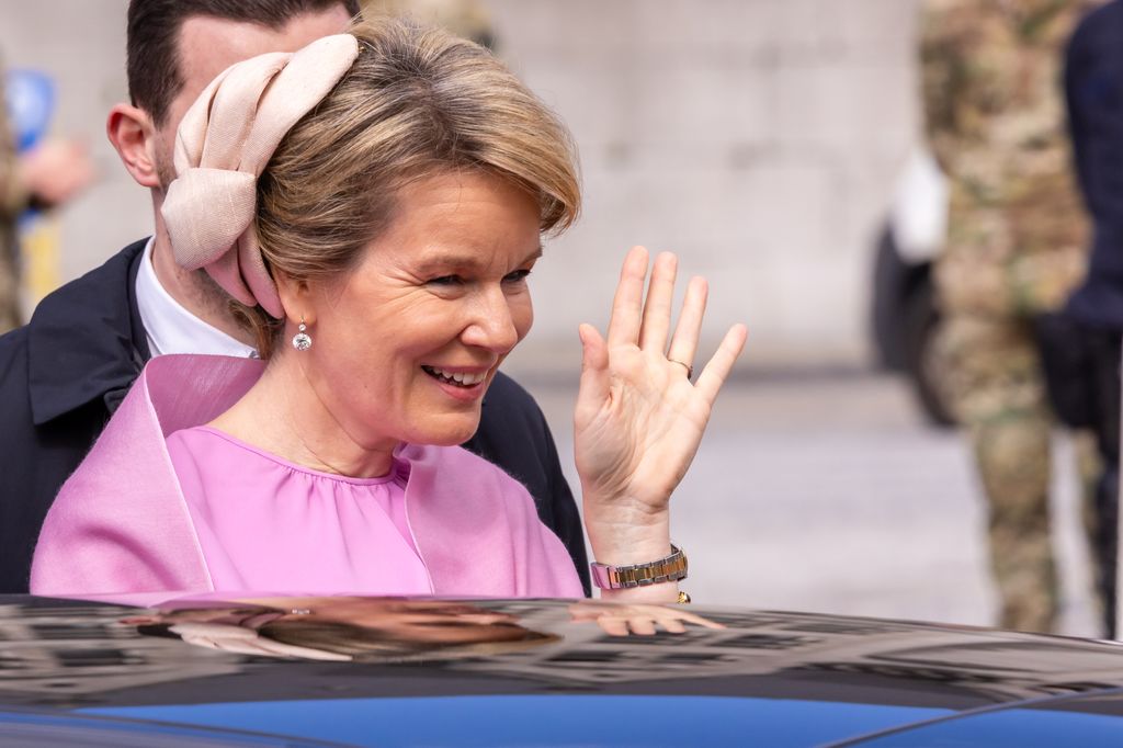Queen Mathilde waving as she gets into a car