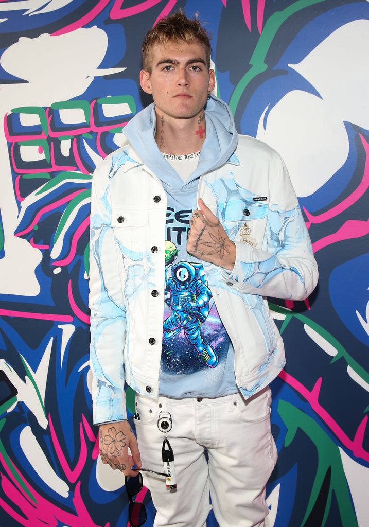 Presley Gerber wearing a blue hoodie and a white denim jacket 