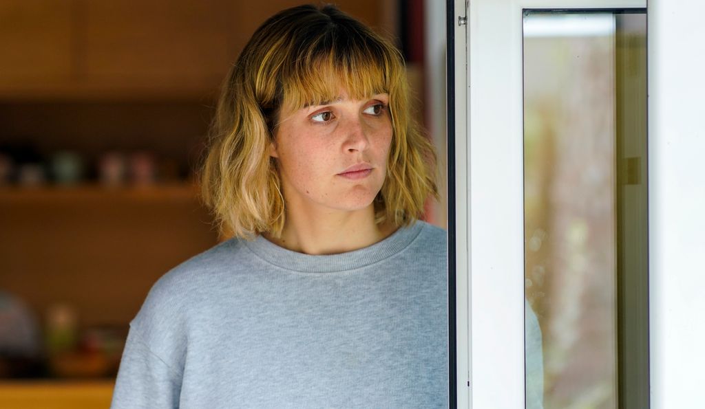 close-up pf blonde woman standing by door