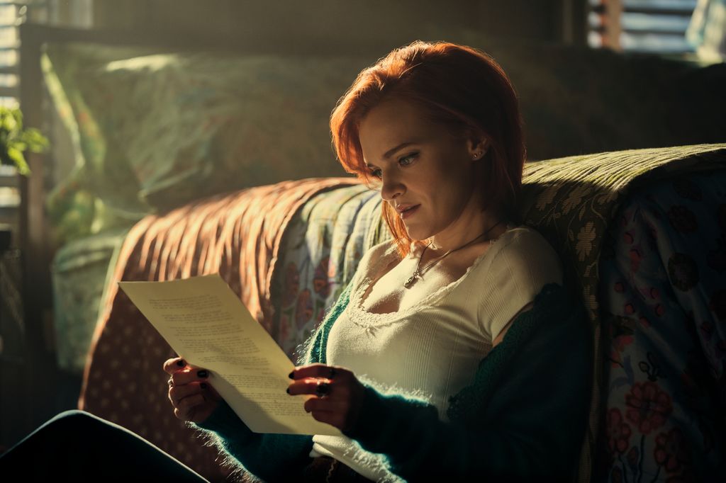 Woman reading paper sitting next to bed