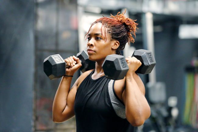 Woman working out in the gym lifting dumb bells