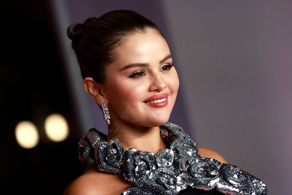 Selena Gomez smiling in a silver dress