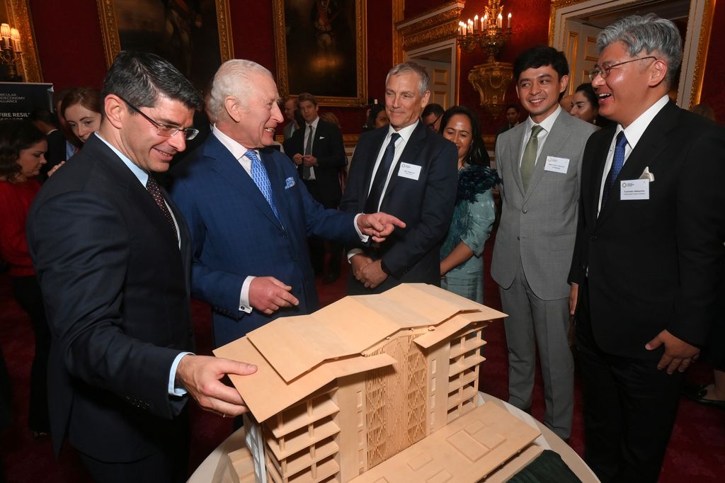 King Charles and men in suits looking at a model