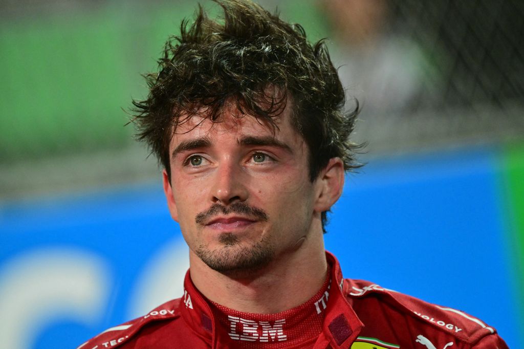 Charles Leclerc avec les cheveux en désordre dans une combinaison de course Ferrari